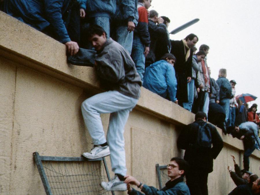 Foto af mennesker der kravler over Berlinmuren