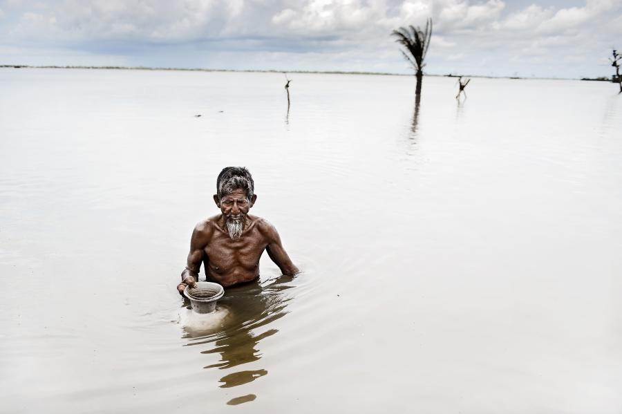En mand fra Bangladesh står med vand til brystet. 