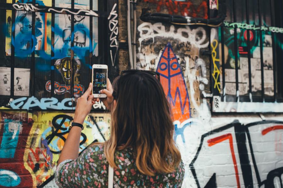 Kvinde fotograferer grafiti med sin mobiltelefon