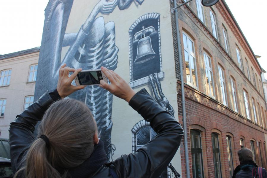 En person tager et billede af et af Aalborgs street art malerier 