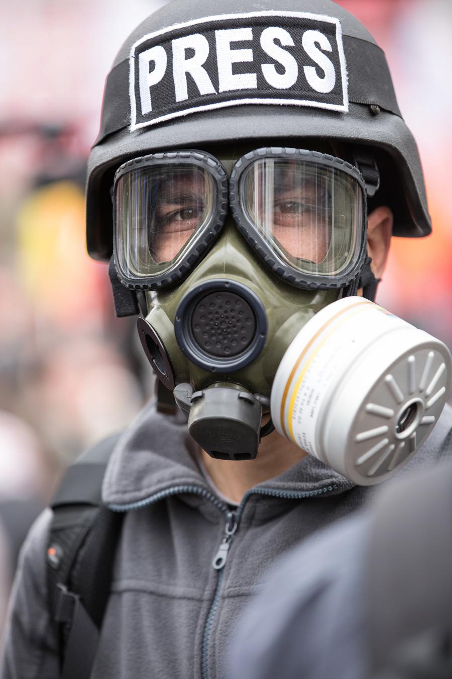 Mand med militærhjelm og gasmaske. Der står "Press" på hjelmen