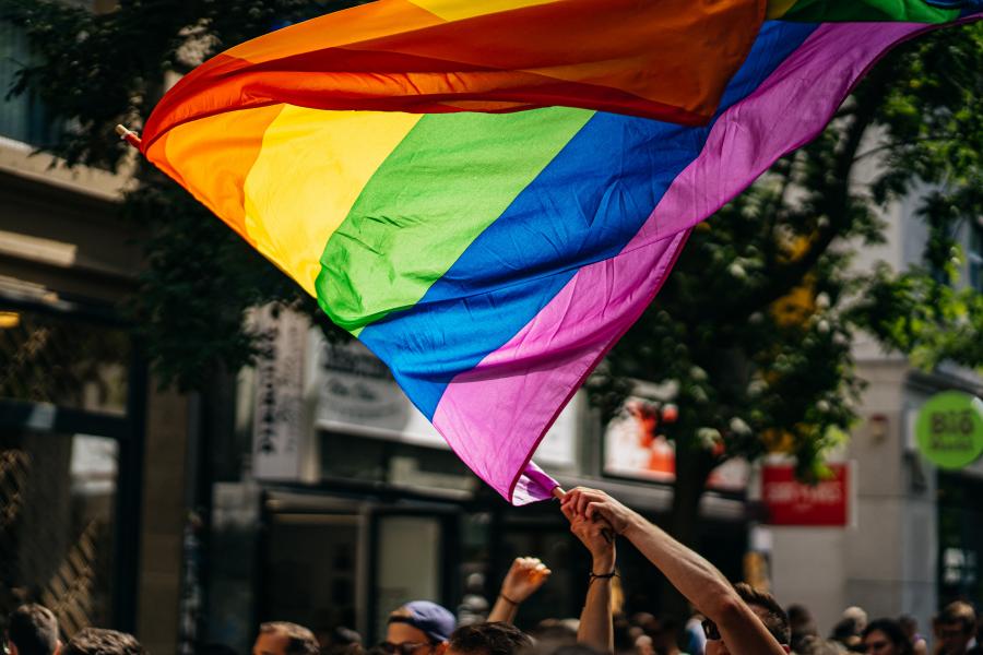 Et regnbueflag vajer over en menneskeflok