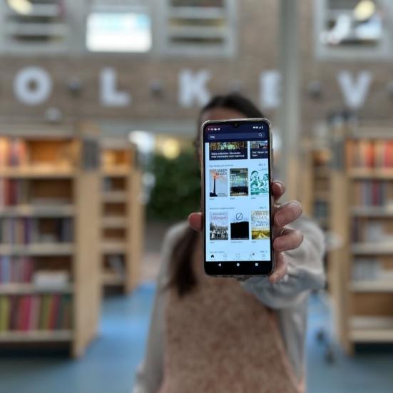 Line holder sin telefon frem til kameraet, telefonen viser app'en Biblioteket