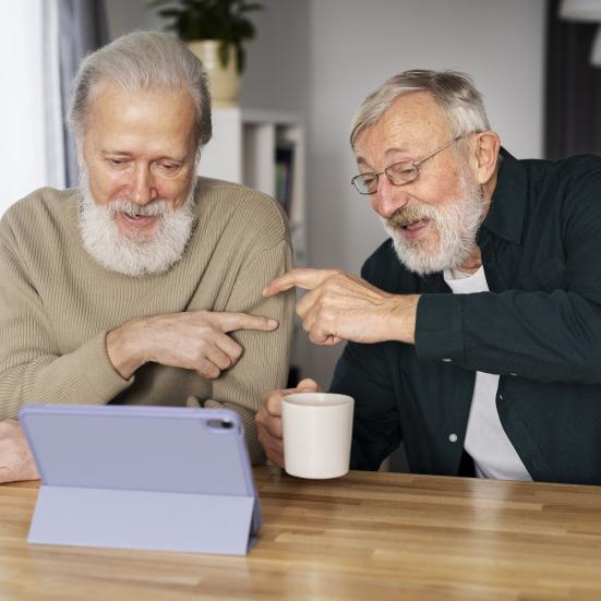 To ældre herrer der snakker sammen over en tablet