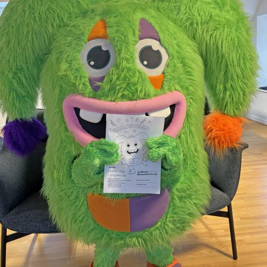 Karnevalsmaskotten Karnevello poserer med en tegning af sig selv.
