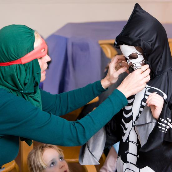 En person er i gang med at iklæde et barn et skeletkostume
