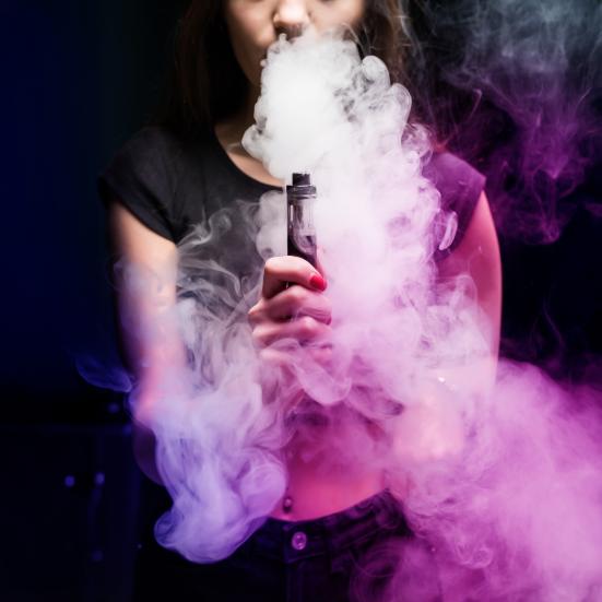 En ung kvinde omhyllet af damp fra en vape pen