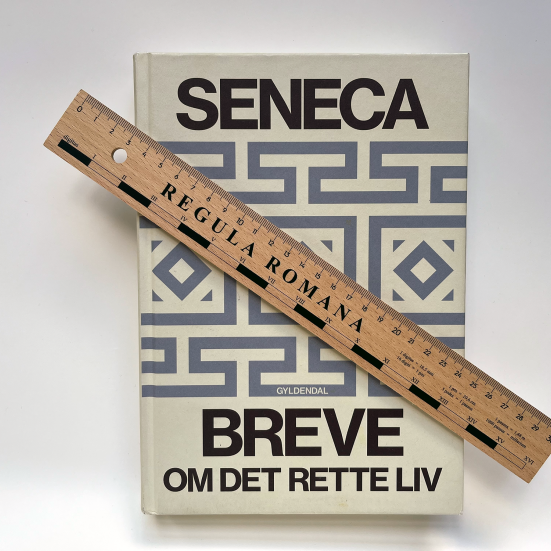 Foto af bogen Breve om det rette liv af Seneca med lineal ovenpå bogen.