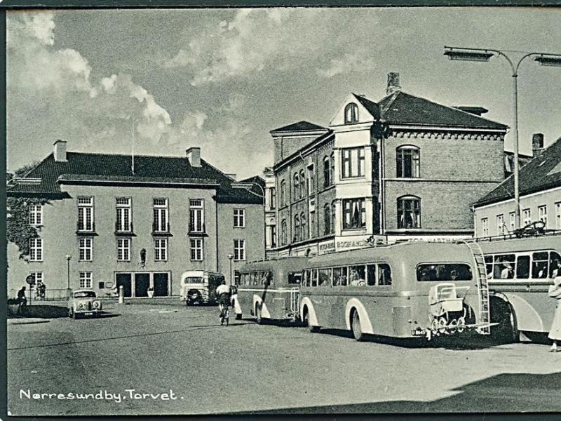 Gammelt sort/hvidt foto af Torvet i Nørresundby. Man kan se byliv med bl.a. busser og mennesker, der går på gaden.