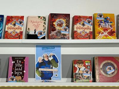 En udstilling med mange bøger med forsiden udad. Det er børnebøger, som har klistermærker på med teksten "Brandvarm anbefaling".