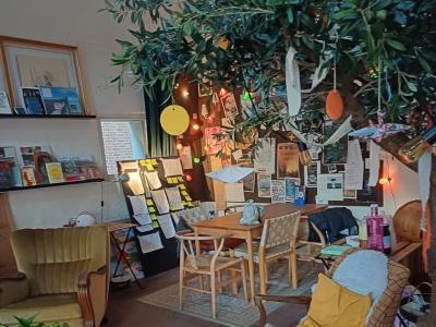 Forstuen i Folkestuen. En lænestol, stuebord og stole, en palme, lamper og andre hyggelige genbrugsmøbler.