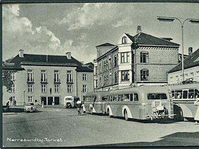 Gammelt sort/hvidt foto af Torvet i Nørresundby. Man kan se byliv med bl.a. busser og mennesker, der går på gaden.