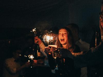 En gruppe mennesker står med champagne og stjernekastere. Det ligner en nytårsfest.