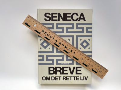 Foto af bogen Breve om det rette liv af Seneca med lineal ovenpå bogen.