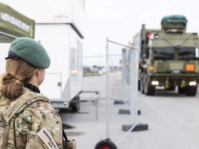 En hjemmeværnssoldat står med ryggen til og kigger på et stort militærkøretøj. 
