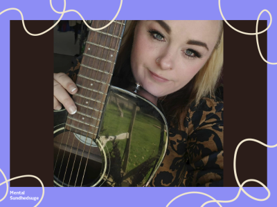 En person poserer sammen med sin guitar