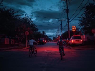 To drenge, der cykler om aftenen på en rødt-oplyst vej