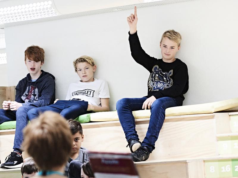 Et barn rækker hånden op, mens en bibliotekar holder en bog op