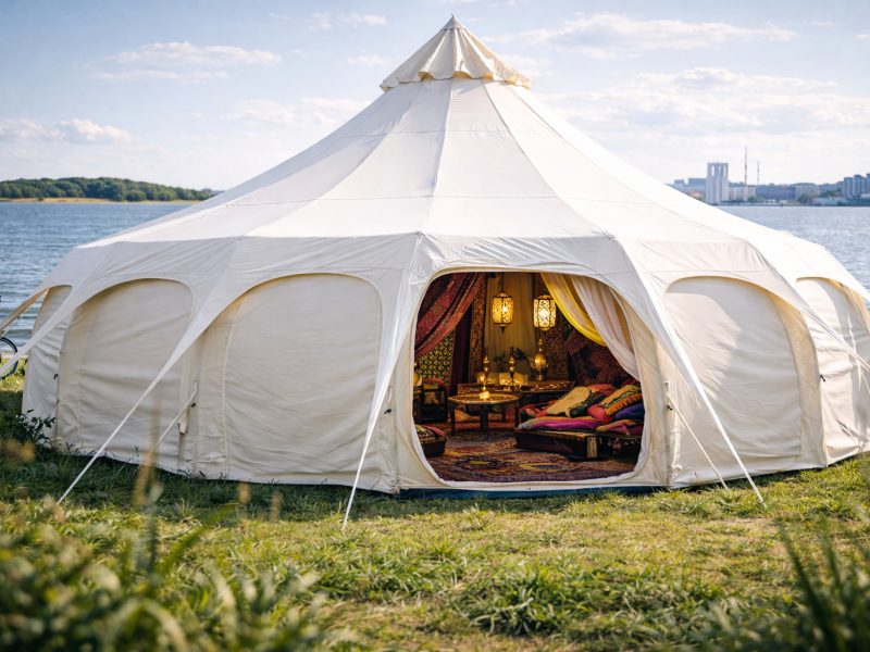 Et stort telt står på en græsplæne med Limfjorden i baggrunden