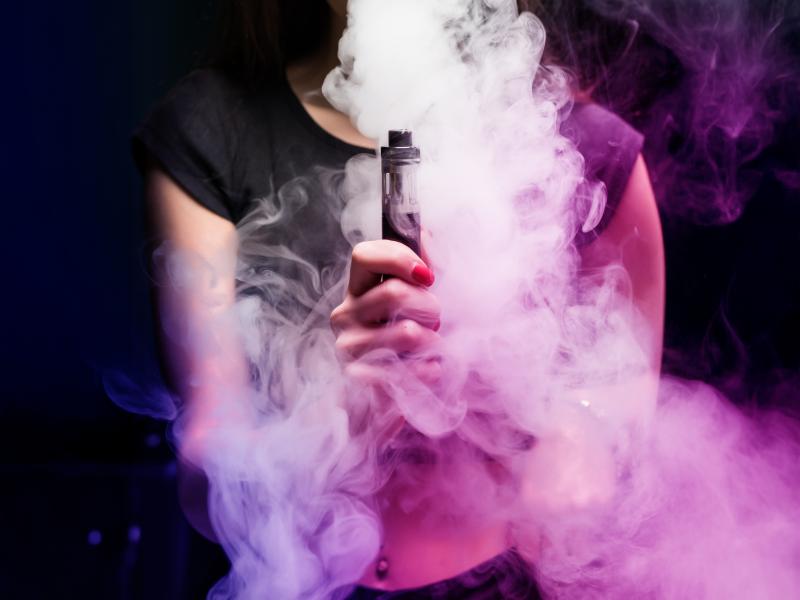 En ung kvinde omhyllet af damp fra en vape pen