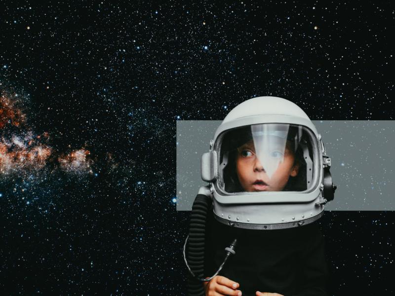 Barn med astronautudstyr ser op med mod en baggrund af stjerner.