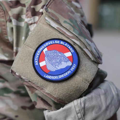 Close-up af en uniformeret overarm med et emplem på. På emblemet står der "Aktiveringsøvelse Blåtand - Landsdelsregion Vest".