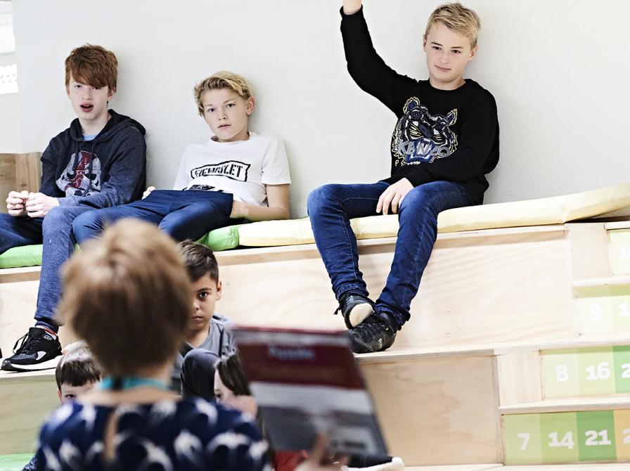 Et barn rækker hånden op, mens en bibliotekar holder en bog op