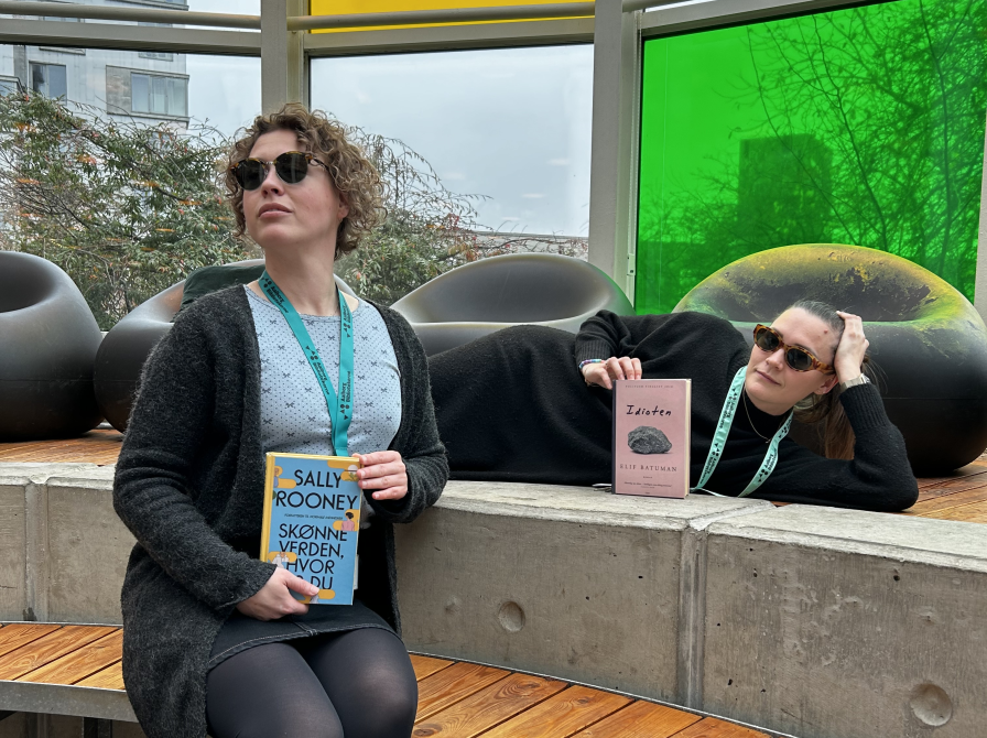 Ditte og Mie sidder i Glashjørnet på Hovedbiblioteket med hver deres bog, som kendte Hollywoodstjerner er blevet spottet med. De har begge solbriller på og ser smarte ud. Ditte sidder på bænken, Mie ligger på reposen.