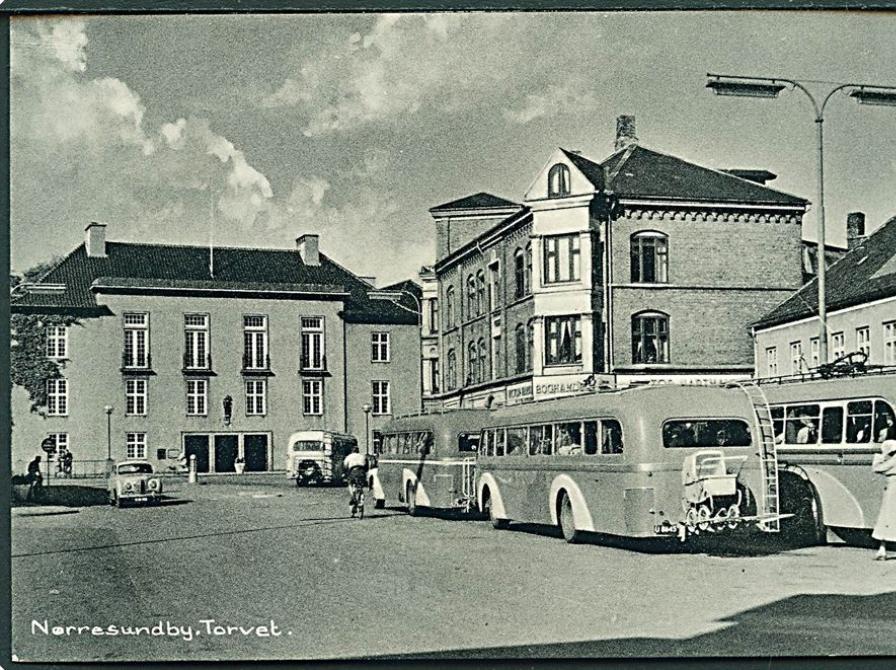 Gammelt sort/hvidt foto af Torvet i Nørresundby. Man kan se byliv med bl.a. busser og mennesker, der går på gaden.