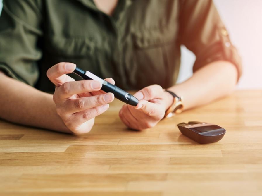 Et menneske sidder ved et bord og er i gang med at teste sit blodsukker.