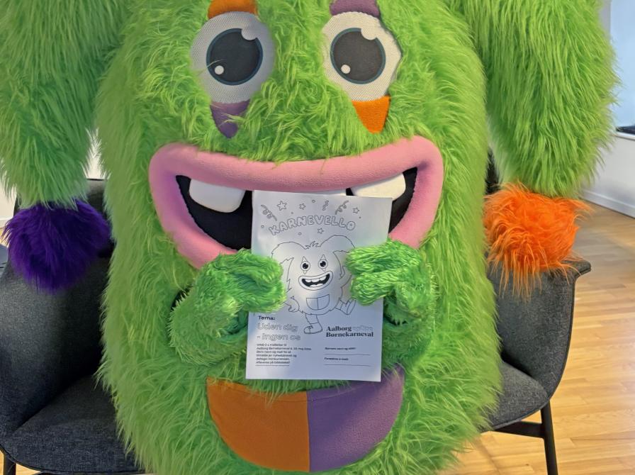 Karnevalsmaskotten Karnevello poserer med en tegning af sig selv.