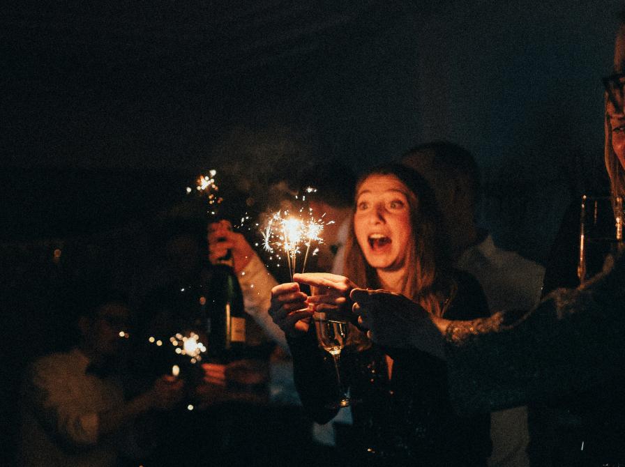 En gruppe mennesker står med champagne og stjernekastere. Det ligner en nytårsfest.