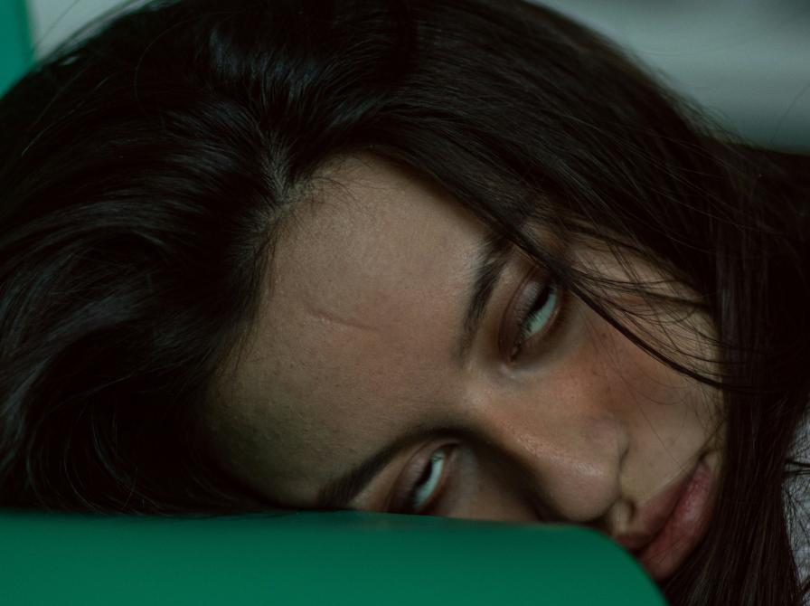 En person ligger med hovedet på en stol og ser ud til, at hun keder sig meget.