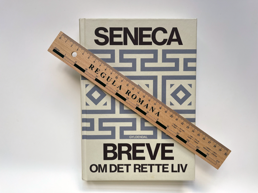 Foto af bogen Breve om det rette liv af Seneca med lineal ovenpå bogen.