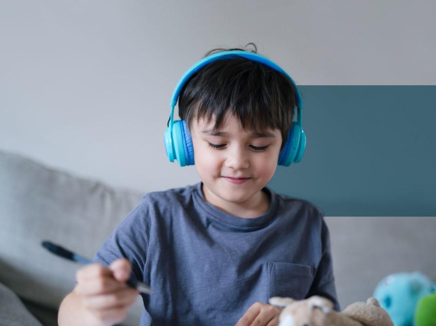 En dreng lytter med høretelefoner på mens han tegner.